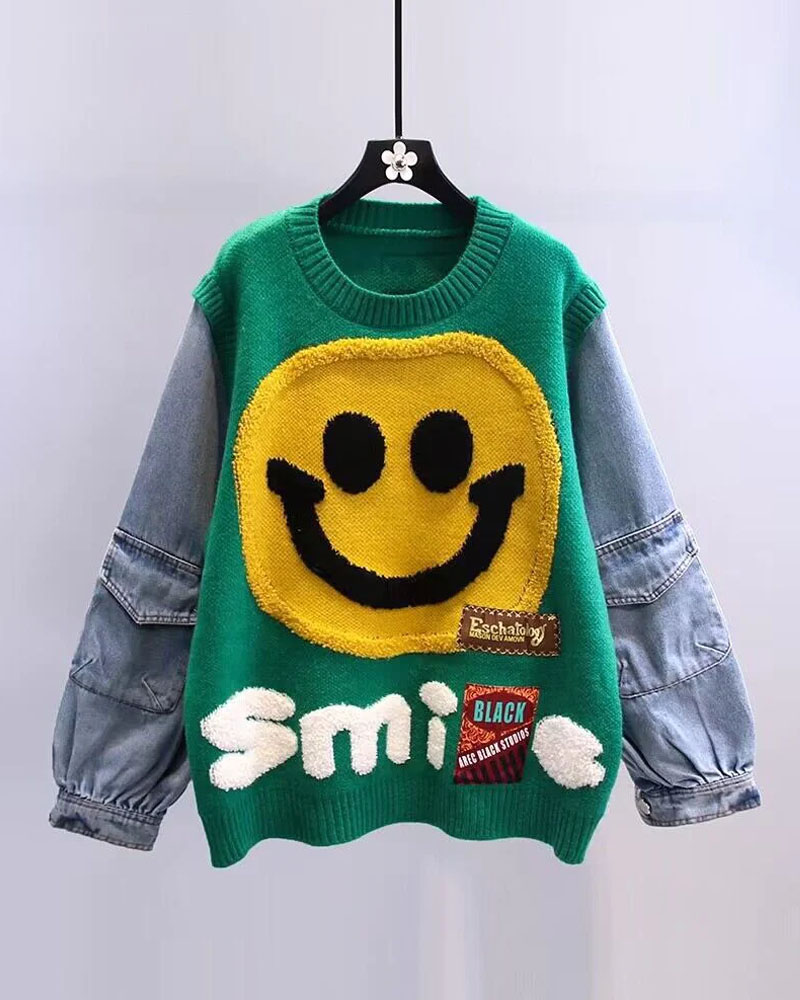Green smiley graphic sweater with denim sleeves displayed on hanger